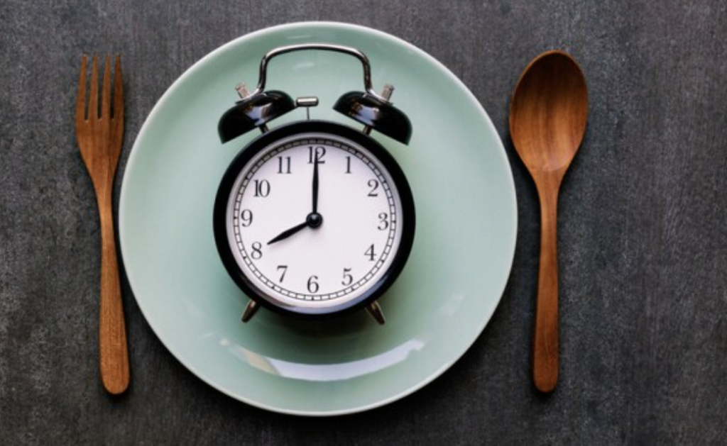 a watch and plate showing food and time restrictions for intermittent fasting 